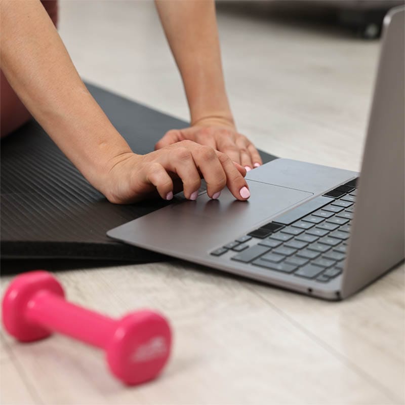 virtual-pilates-class Woman using a computer to sign into a Zoom account for a Group Pilates Mat class